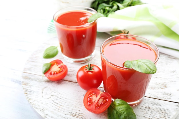 Verres de jus de tomates fraîches sur une table en bois agrandi