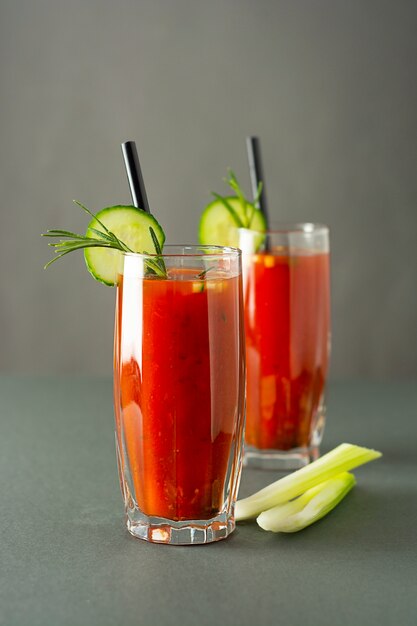 Verres de jus de tomates savoureuses isolé sur une table grise