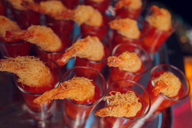 Verres à liqueur de crevettes à cocktail individuels avec une délicieuse sauce épicée tartare maison décorée de feuilles de persil sur un plateau blanc sur un tapis de table pour le dîner de Noël ou un cocktail en gros plan