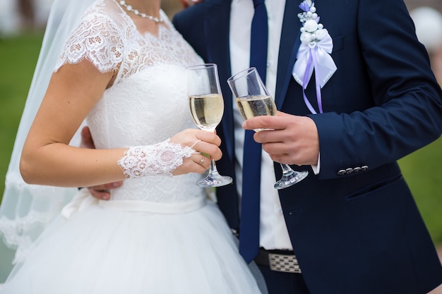 Verres de la mariée et le marié dans les mains en gros plan avec champagne