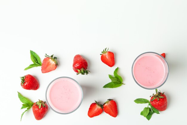 Verres de milk-shake aux fraises et ingrédients sur fond blanc