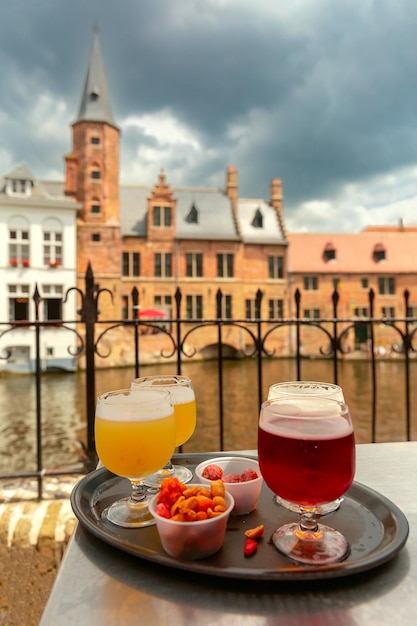 Des verres multicolores avec de la bière et des collations sur le fond de la ville médiévale de Bruges, en Belgique