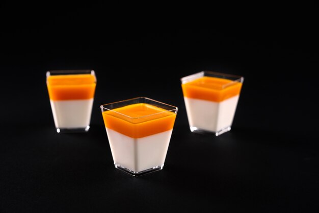 Verres avec panna cotta isolé sur fond noir.