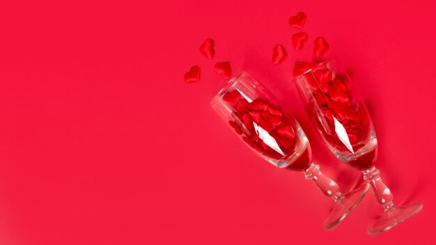 Verres avec petits coeurs rouges sur fond rouge atmosphère romantique copie espace