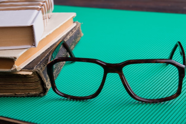 Verres De Plan Rapproché Et Pile De Vieux Livres Sur Le Fond Vert