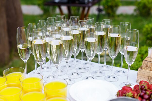 Verres rembourrés avec champagne se rangent sur la table. Fête de mariage, restauration en plein air. Boissons, jus et fruits - banquet festif, réception