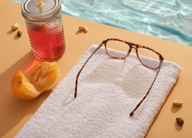 Les verres reposent sur une serviette blanche avec vue sur la mer tropicale transparente scintillante. Cocktail vivifiant, orange tranchée juteuse, noix éparpillées. Idée ensoleillée de détente sur la plage d'été.