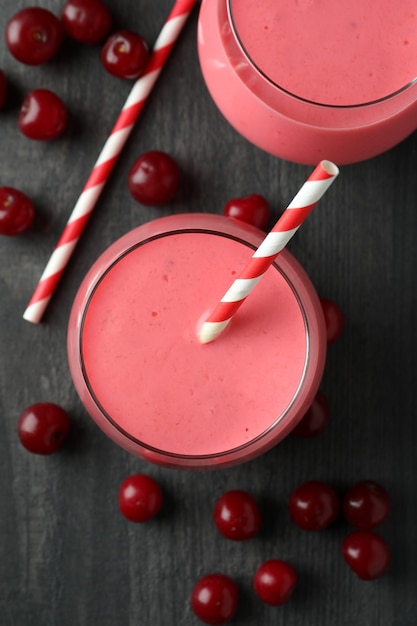 Verres de smoothie cerise et ingrédients sur table en bois foncé