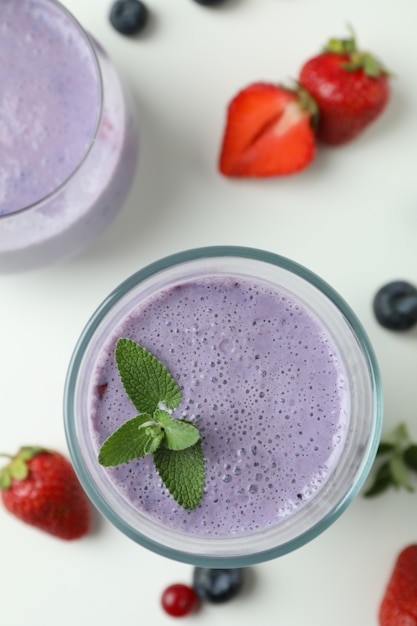 Verres de smoothie et ingrédients sur fond blanc