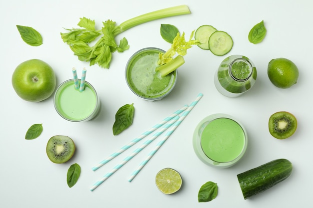 Verres de smoothie vert et ingrédients sur fond blanc, vue du dessus