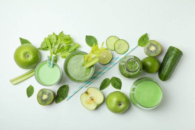 Verres de smoothie vert et ingrédients sur fond blanc, vue du dessus