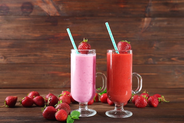 Verres de smoothies aux fraises fraîches sur table en bois