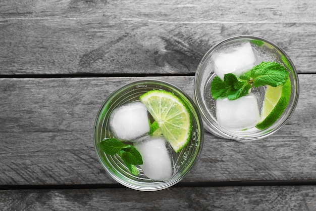 Verres de soda au citron avec de la glace sur une table en bois rustique