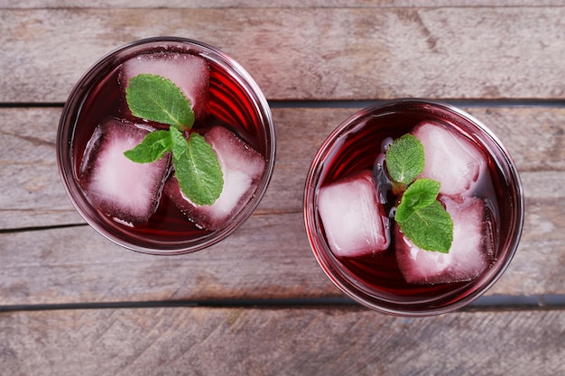 Des verres de soda à la cerise avec de la glace et de la menthe fraîche sur un fond en bois rustique