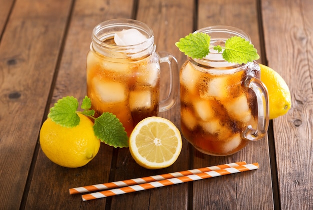 Verres de thé glacé avec des citrons frais sur table en bois