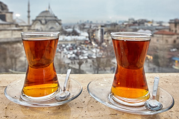 Des verres de thé turcs sont placés dans des soucoupes avec des cuillères contre le paysage urbain d'Istanbul.