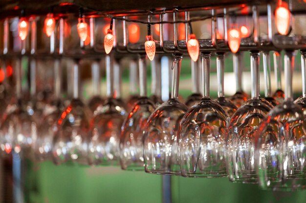 Des verres en verre avec des lumières rouges sont suspendus au bar. photo de haute qualité