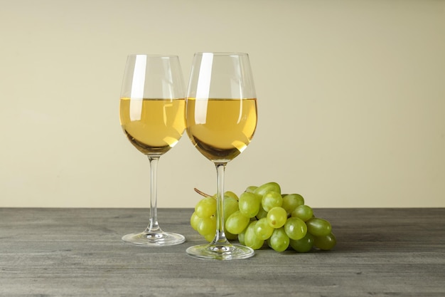 Verres de vin blanc et de raisin sur une table texturée grise