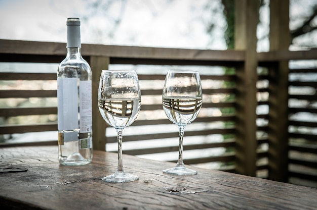 Verres à vin blanc sur table en bois sur terrasse