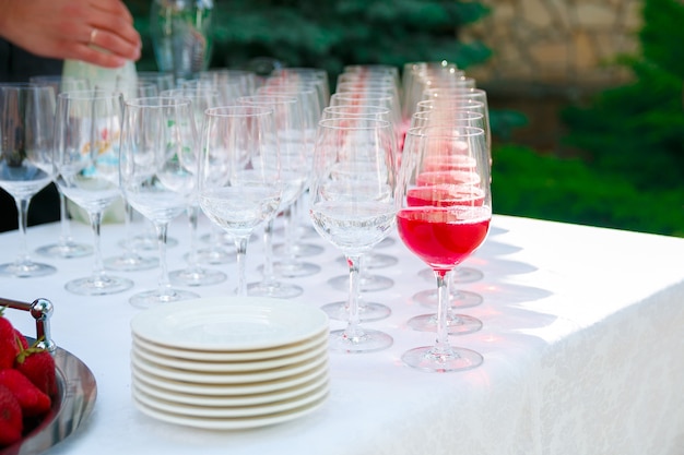 Verres de vin, champagne, assiettes et baies sur la nappe blanche