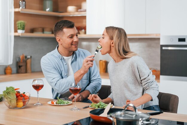 Avec des verres de vin Couple préparant la nourriture à la maison sur la cuisine moderne