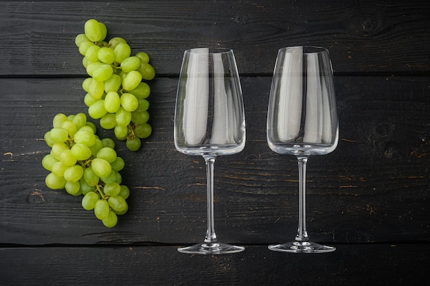 Verres à vin avec ensemble de raisins, sur table de table en bois noir, vue de dessus à plat