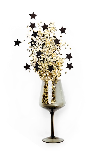 Verres à vin noirs avec des confettis dorés et des étoiles noires sur fond blanc. Mise à plat, vue de dessus. Concept de vacances et de célébration.