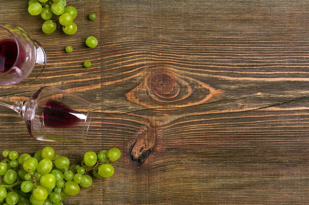 Verres de vin et raisins mûrs isolés sur une table en bois