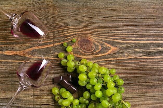 Verres de vin et raisins mûrs isolés sur une table en bois