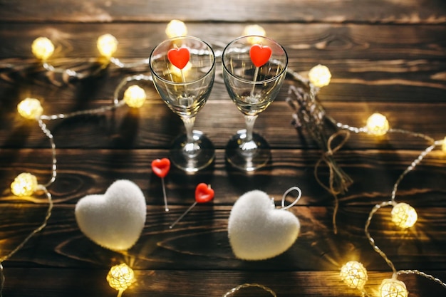 Verres à vin romantiques avec des coeurs pour la Saint-Valentin Rendez-vous romantique et dîner Lumières confortables Fond en bois Carte postale de vacances Concept d'amour