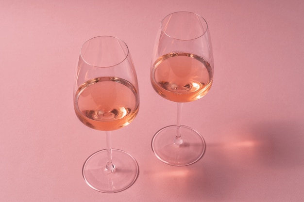 Verres de vin rosé sur table rose, vue de dessus.