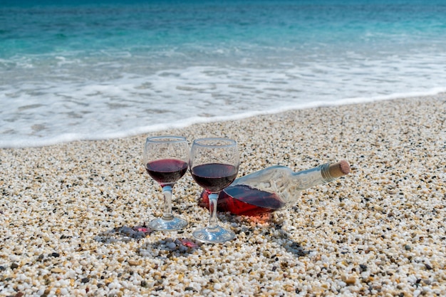 Verres de vin rouge et bouteille sur la plage à la journée ensoleillée d'été