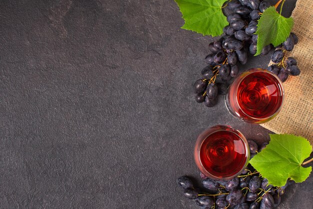 Verres de vin rouge et de raisin bleu sur la vue de dessus de fond noir