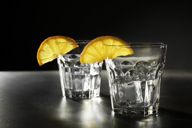 Verres de vodka au citron et glace sur fond sombre