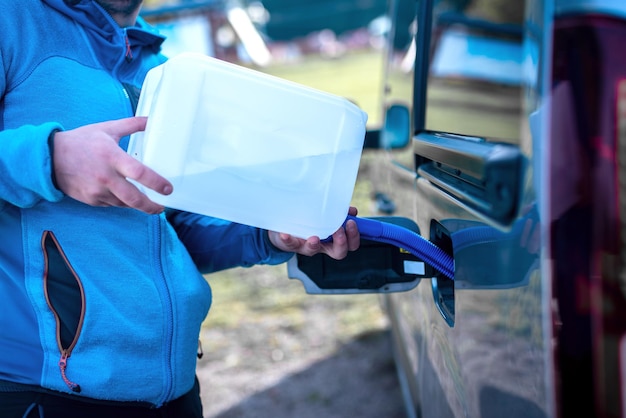 Verser de l'adblue dans la voiture Conducteur masculin ajoutant du liquide d'échappement diesel à sa voiture