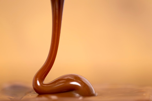 Verser le caramel au lait caramel étalé avec une cuillère sur fond doré, doux connu sous le nom de Cajeta