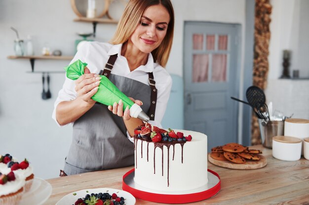 Verser de la crème. Une femme se tient à l'intérieur dans la cuisine avec une tarte maison.