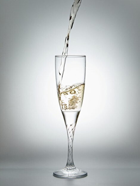 Photo verser du champagne dans un verre sur fond gris