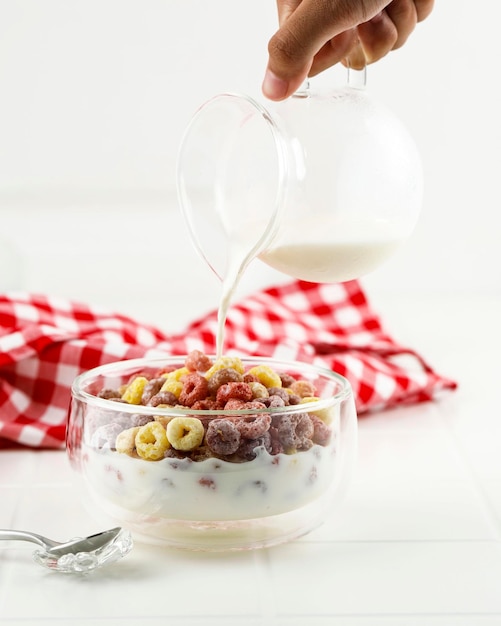 Verser du lait dans le bol avec Froot Loops céréales colorées Kids Breakfast Concept Fond blanc