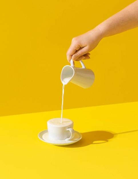 Verser du lait dans une tasse sur fond jaune Débordement de lait d'une tasse