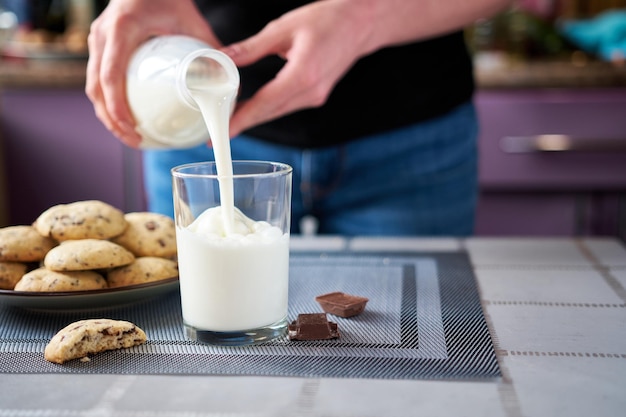 Verser du lait dans un verre avec des biscuits au chocolat faits maison sur fond