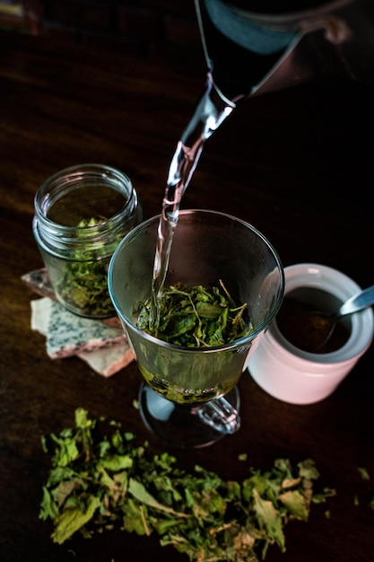 Verser du liquide dans un verre en verre avec des feuilles sèches