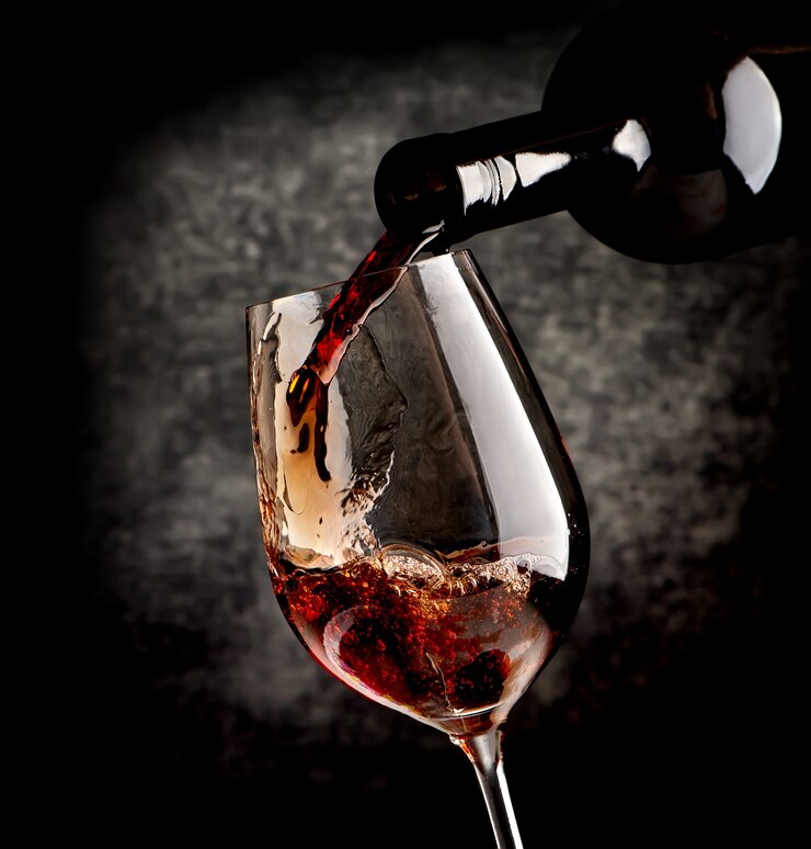 Verser du vin dans un verre à vin sur fond noir