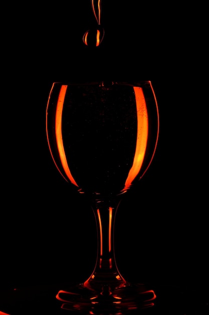 Verser de l'eau dans un verre sur fond noir. Eau d'orange dans un verre