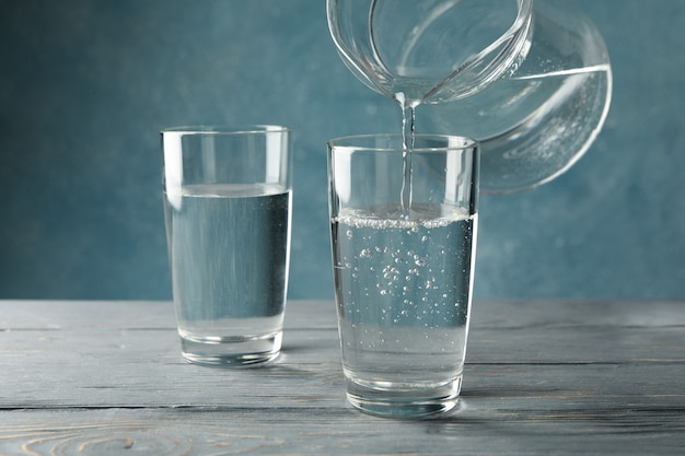 Verser de l'eau fraîche purifiée de la cruche en verre sur une table en bois