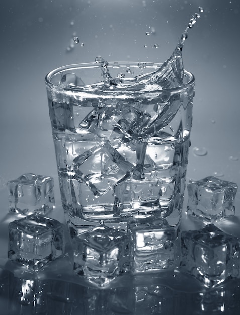 Verser un glaçon dans un verre d&#39;eau. éclaboussures d&#39;eau.