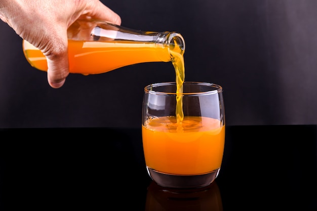 verser le jus d&#39;orange à la main d&#39;une bouteille dans un verre