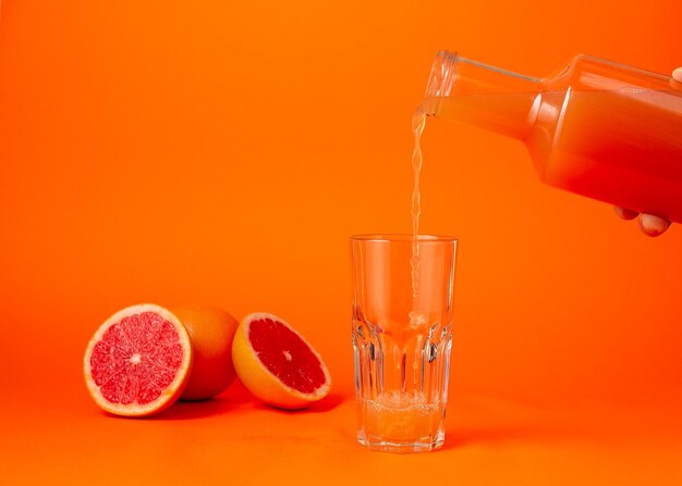 Verser le jus de raisin dans le verre sur fond dégradé orange