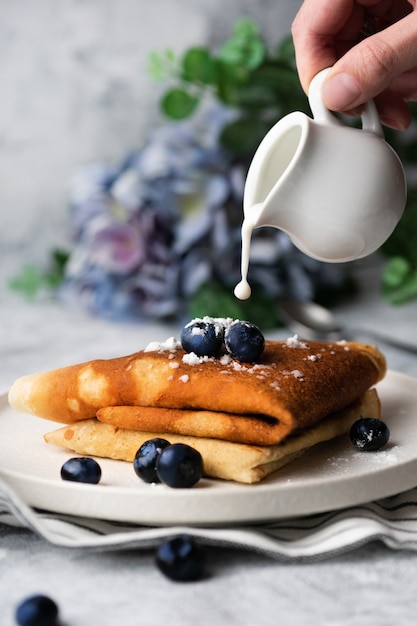 Verser le lait sur de délicieuses crêpes dans une assiette