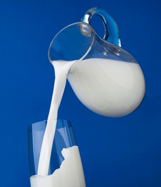Photo verser le lait avec des éclaboussures sur fond bleu